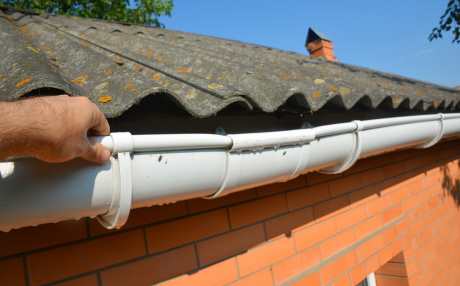 Hand of a roofing technician repairing and securing gutter joints